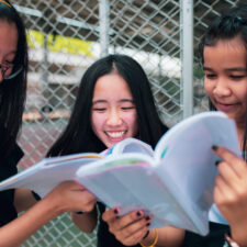 Asian,Teenager,Holding,School,Book,And,Laughing,With,Happiness,Emotion